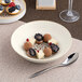 A round, deep coupe porcelain plate in brown and cream, shown with a dessert arrangement.