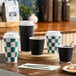A set of black double wall ripple paper hot cups, some with lids, displayed on a wooden surface.