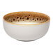 A round porcelain coupe bowl with a cream exterior and a brown spotted rim.