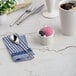 A small ivory round porcelain ramekin filled with a scoop of pink ice cream and blueberries, placed on a marble surface.
