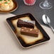 A brown rectangular porcelain platter with an embossed wide rim, shown holding two assorted desserts.