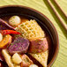 A bowl of soup containing honeycomb beef tripe, sweet potatoes, pearl onions, and red chili peppers.