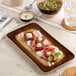 A brown rectangular wide rim porcelain platter with a food presentation.