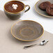 A brown round rimless porcelain tea cup saucer with a speckled pattern.