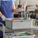 A gray polyethylene plastic bus tub holding dishes and glassware on a service cart.
