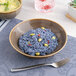 A brown round porcelain coupe deep plate filled with blue rice and yellow beans.