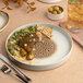A round porcelain plate with a brown and cream design and a raised rim.