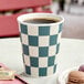 A 12 oz. double wall ripple paper hot cup with a navy checkered pattern.