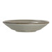 A round, shallow porcelain coupe plate with a subtle textured design and a neutral, earthy glaze.