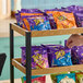 A display shelf with various flavors of Takis Rolled Tortilla Chips in small 1 oz. bags.