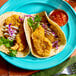 A plate with two tacos filled with breaded grouper tenders, shredded cabbage, sauce, and a side of salsa.