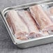 A stainless steel tray containing several vacuum-sealed frozen boneless skinless mahi mahi steaks.