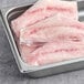 A stainless steel tray containing several frozen, skinless grouper fillet portions.