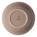A beige round porcelain coupe deep plate shown from the bottom with the Ariane brand logo.