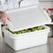 A chef holding a Tablecraft white plastic container with food in it.