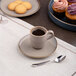 An Ariane Splash Beige 3 oz. beige porcelain espresso cup on a matching saucer.