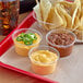 A table with bowls of Muy Fresco cheddar cheese sauce and chips.