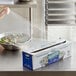 A box of Choice Safecut 18-inch by 2000-foot premium foodservice film with a slide cutter being used to cover a bowl of salad.
