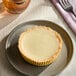 A small key lime pie with a smooth, creamy filling in a pastry crust, served on a plate.