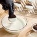 A bowl of melted vanilla compound coating being used to dip a chocolate sandwich cookie.