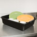 A black Tablecraft bus tub with plates and cups inside.