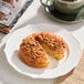 A round vegan cinnamon sugar crumb cake with a crumbly topping, served on a white plate.