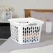 A white square plastic laundry basket with handles, partially filled with clothes.