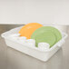 A white Tablecraft polyethylene plastic bus tub with green and yellow plates and cups inside.