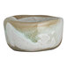 A small, organic-shaped stoneware ramekin with a natural beige and white glaze.