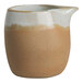 A small, two-toned stoneware creamer with a natural beige base and a white glazed top, featuring a spout for pouring.