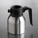 A stainless steel insulated coffee server with a black plastic handle and lid.