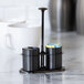 A black onyx stainless steel sugar stick holder and creamer set with two compartments and a central handle.