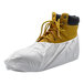 A yellow work boot covered by a white disposable microporous shoe cover.