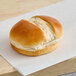 A sliced milk bun with a soft, golden-brown top placed on a sheet of parchment paper.
