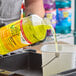 A bottle of CloroxPro Pine-Sol Lemon Fresh Scent Multi-Surface Cleaner being poured into a white bucket.