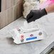 A package of Clorox Healthcare Bleach Germicidal Wipes being dispensed by a person wearing a black glove.