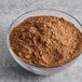 A clear glass bowl filled with light brown carob powder.