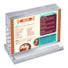 An acrylic block frame with a landscape orientation, displaying a colorful drink menu, mounted on a clear acrylic base.