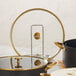 A round tempered glass pot cover with gold accents and a metal handle.