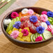 A bowl of poke topped with colorful Fresh Origins Bachelor's Button edible flowers, sliced vegetables, and diced fruit.