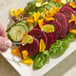 A plate of salad garnished with Fresh Origins Premium Confetti Edible Flowers, featuring colorful flower petals on top of sliced beets, cucumbers, and greens.