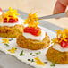 A plate of breaded appetizers topped with cream, roasted tomato, and Fresh Origins Micro Marigold edible flowers.