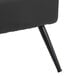 A close-up of a black faux leather accent chair with a black metal leg.