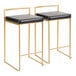 A pair of gold steel counter height stools with low backs and black faux leather seats.