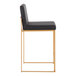 A modern counter height stool with a gold steel frame and a black faux leather seat and back.