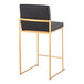 A modern counter height stool with a gold steel frame and a black faux leather back and seat.