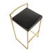 A gold steel barstool with a low back and a black faux leather seat.