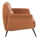 A camel-colored faux leather accent chair with black metal legs.