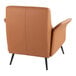A camel-colored faux leather accent chair with black metal legs.