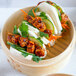 A bamboo steamer basket containing bao buns filled with plant-based vegan dusted scallops, cucumber, carrots, cilantro, and sesame seeds.
